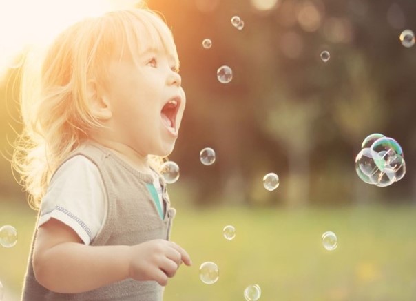 Image d'un petit enfant qui joue avec des bulles à l'extérieur